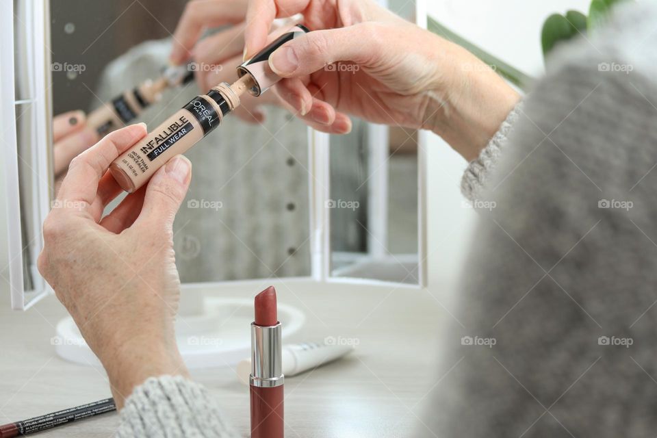 Middle-aged Caucasian woman is going to use make-up concealer