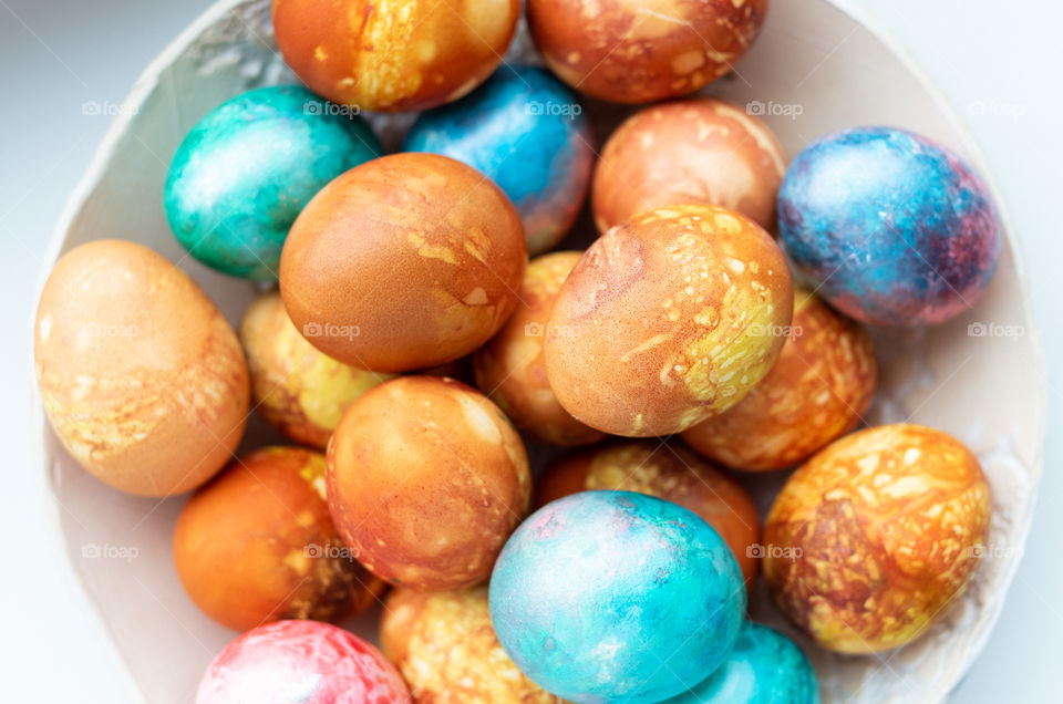 Top view of colourful Easter eggs in a bowl.