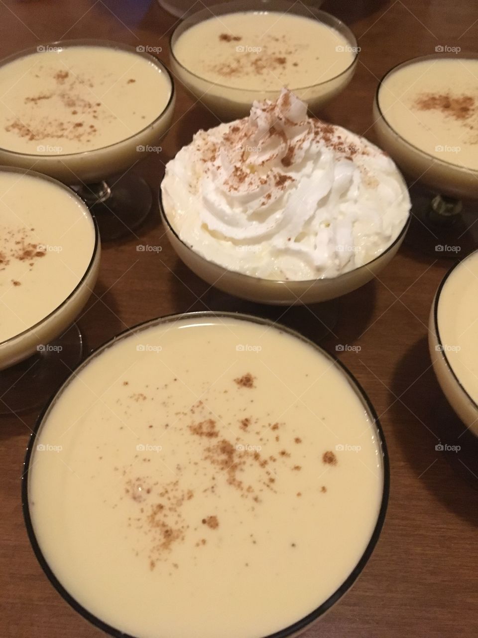 Glasses of eggnog on a table with whipped cream and cinnamon 