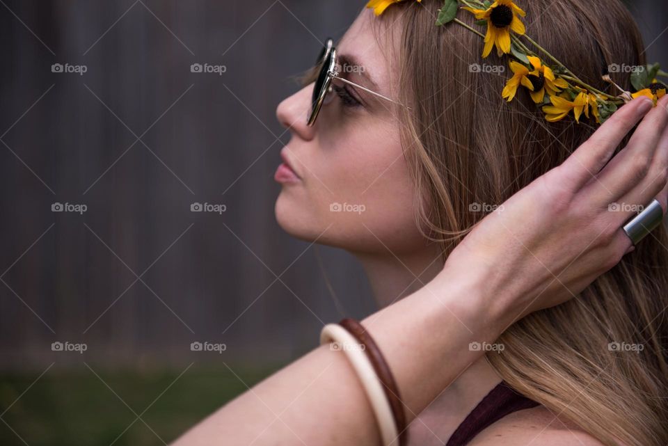 Profile portrait of a millennial woman wearing a flower crown and retro sunglasses 