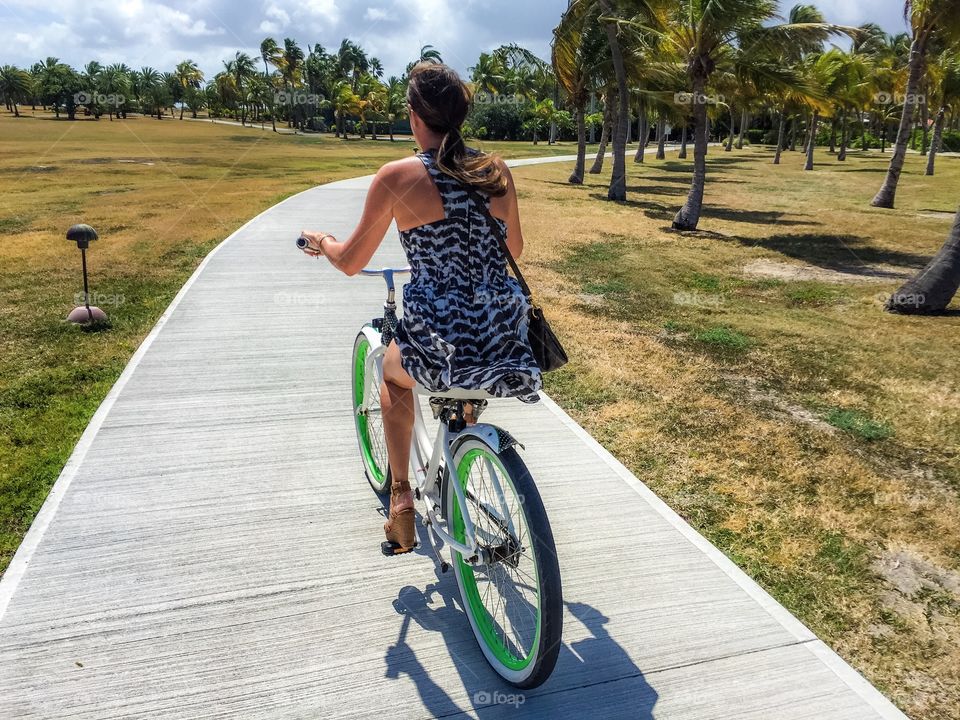 Rear view of a woman cycling on walkway