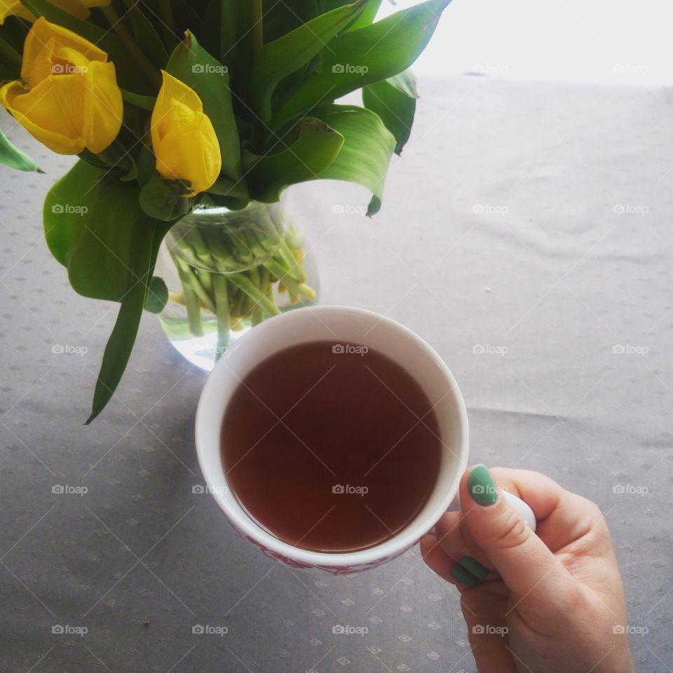 Hand holding tea with tulip flowers