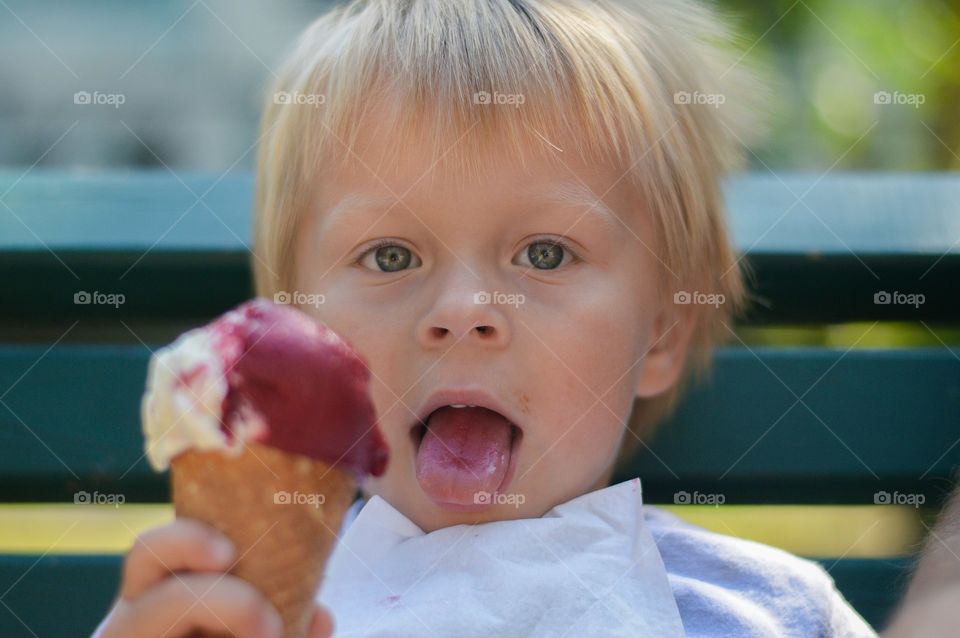 Toddler boy eating icecream on hot summer day.
