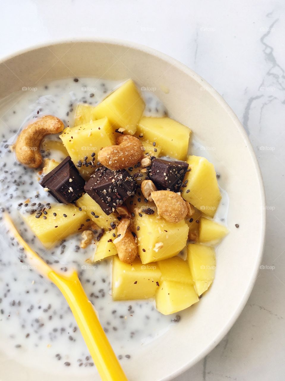 Fresh Fruit Smoothie : Healthy breakfast bowl with mango chia seed, yogurt, dark chocolate and cashew nuts.