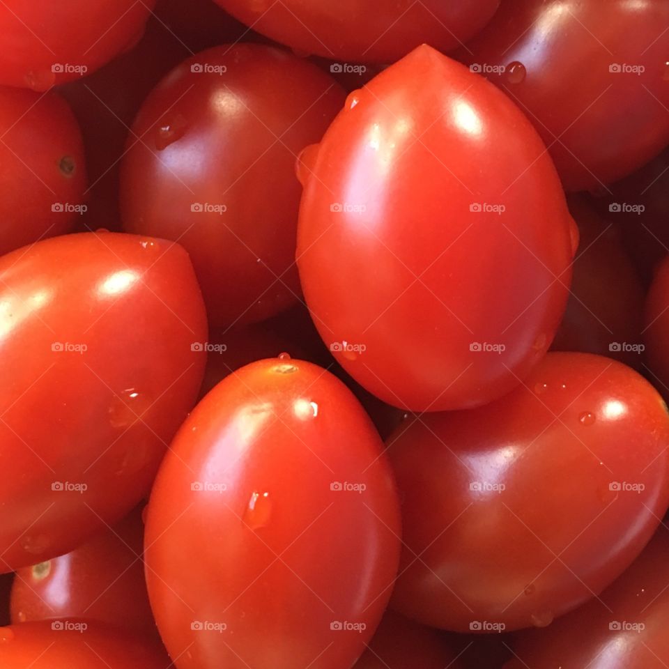 Fresh from the garden-up close.  Cherry sized red, ripe tomatoes are piled up.  