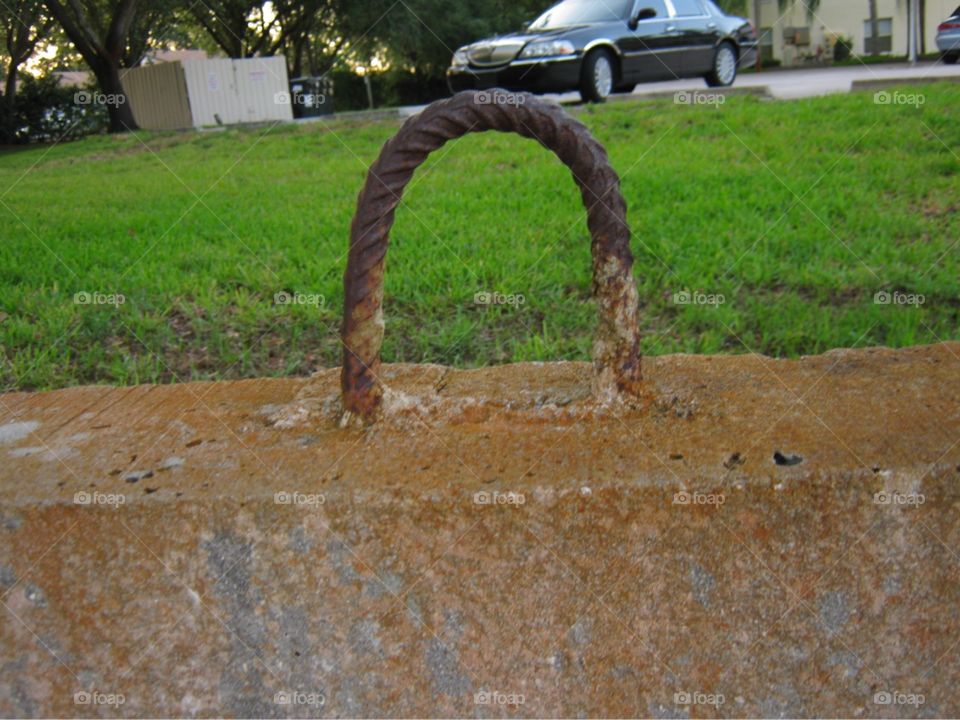 A rusty metal rod protruding from a block of concrete. The photo was taken in Bonita Springs, Florida