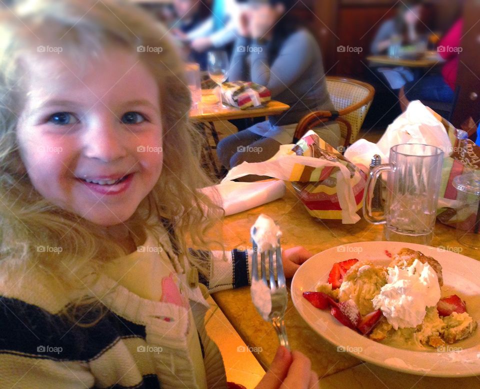 Small girl eating cake in restaurant