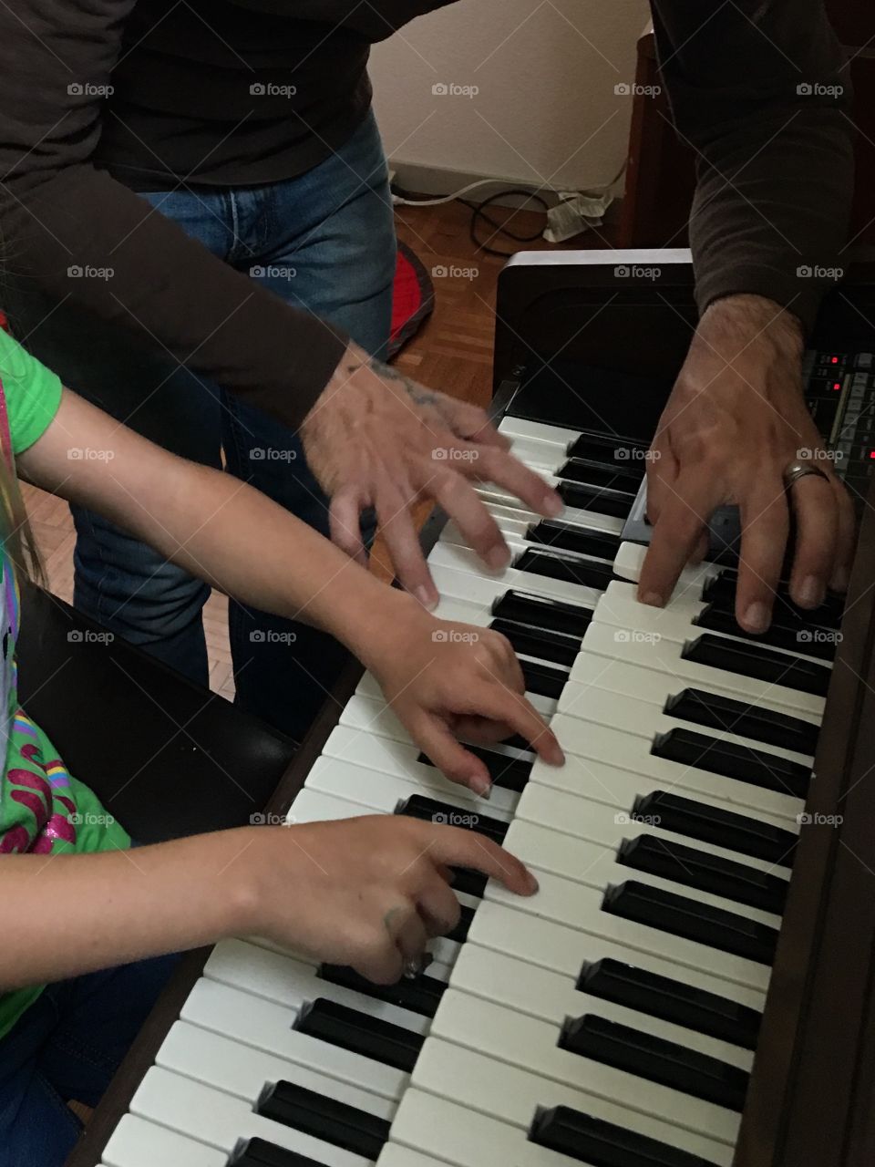 Father and daughter hands playing the organ together. 