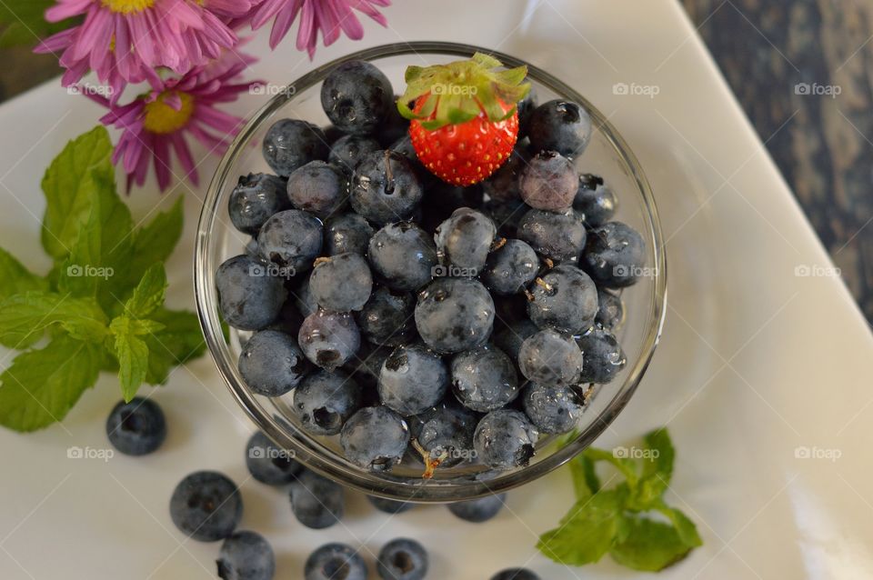 bowl of blueberries with a strawberry