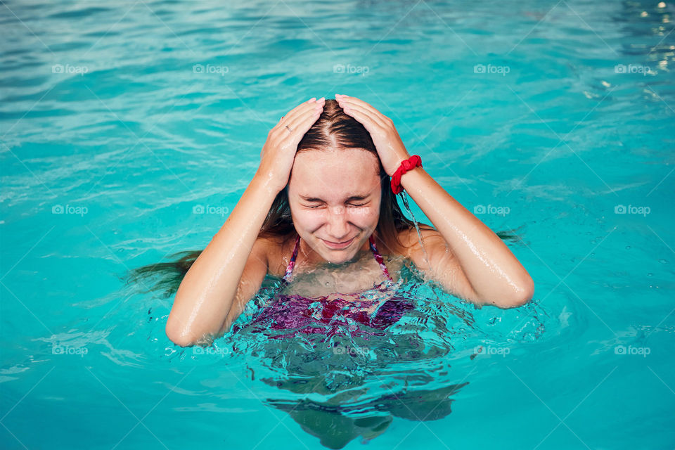 Young woman swimming and relaxing in swimming pool. Candid people, real moments, authentic situations