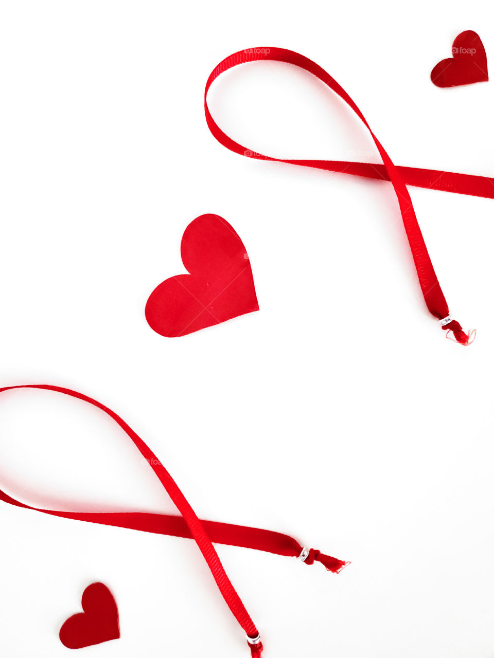 Heart Disease Awareness flatlay:  two red ribbons and three hearts on a white background.