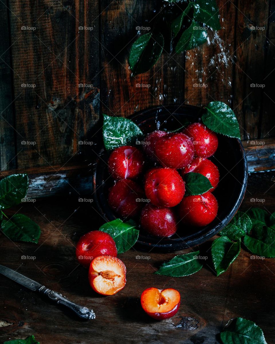 Red plums on the wooden background. Eco-concept.