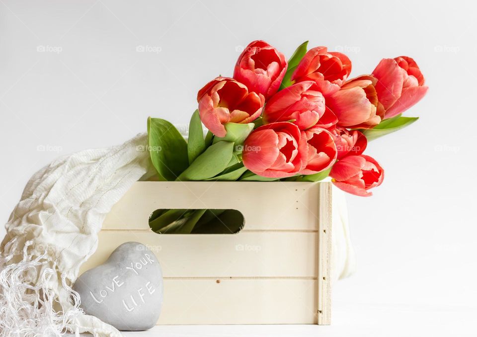 A bouquet of fresh cut red tulips in a wooden crate