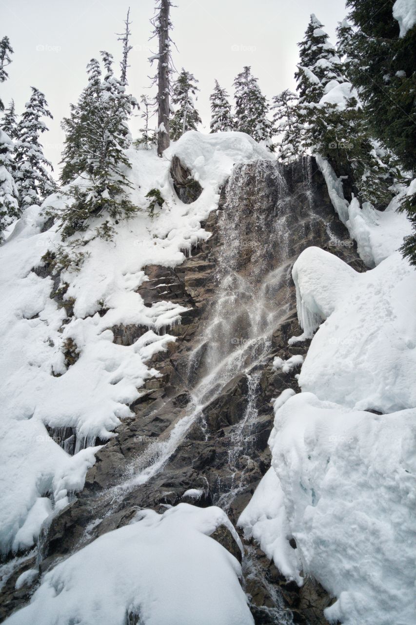 Winter Waterfall on Snow Covered Mountain