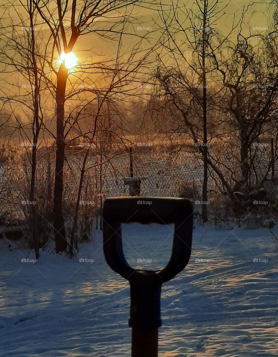 colorful sunrise in winter garden with snowshovel