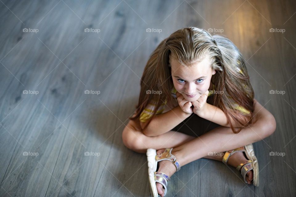 Teenage girl sitting on floor and looking at camera