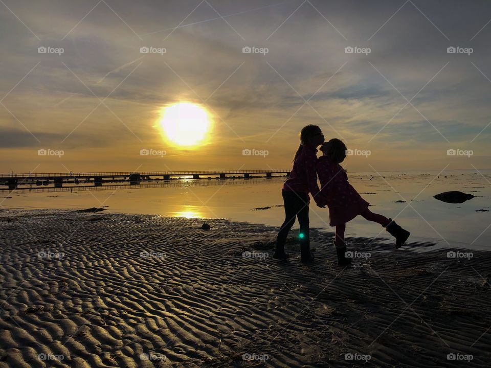 Young sisters kiss at sunset
