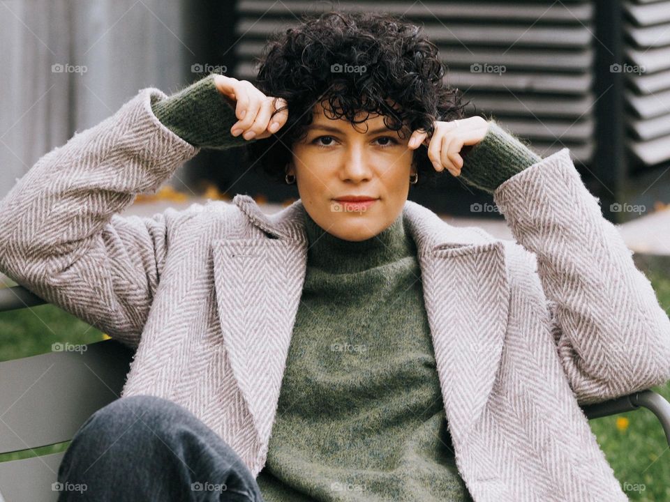 Portrait of young beautiful woman with dark curly hair, looking at camera 