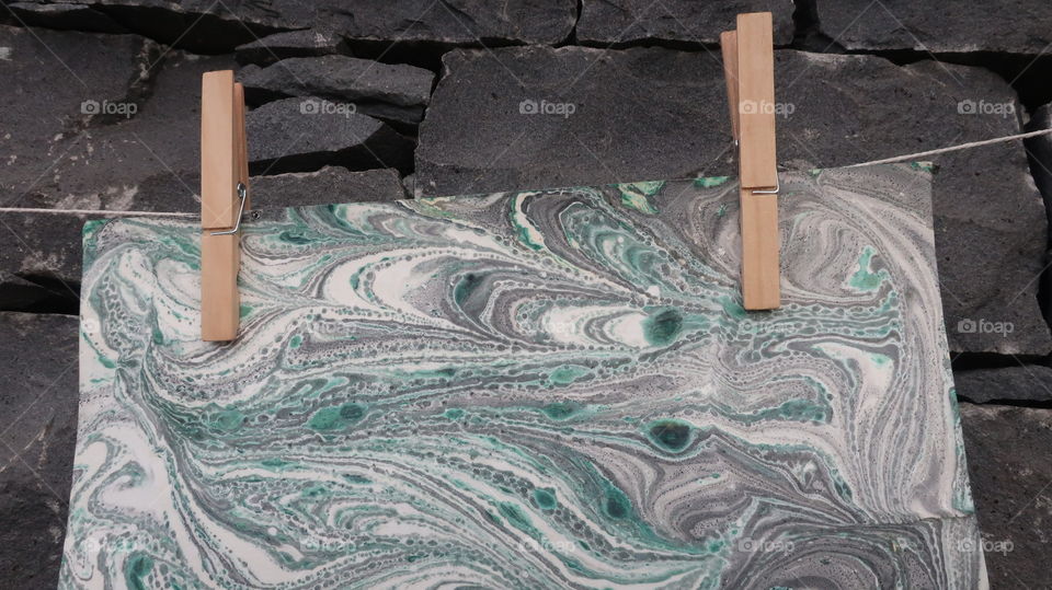 Marble papers drying in front of stone wall