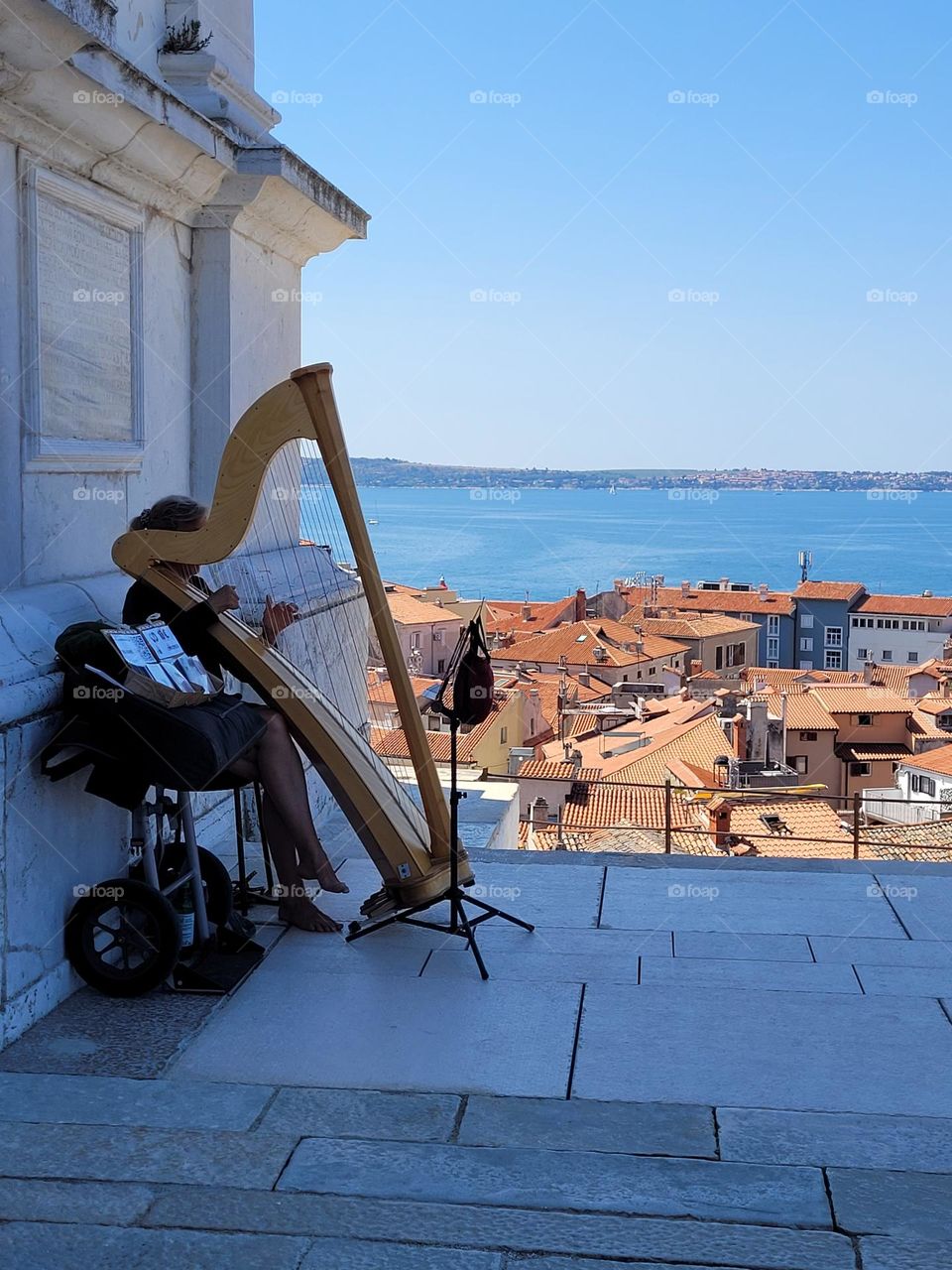 Harpist playing with view on city and sea.