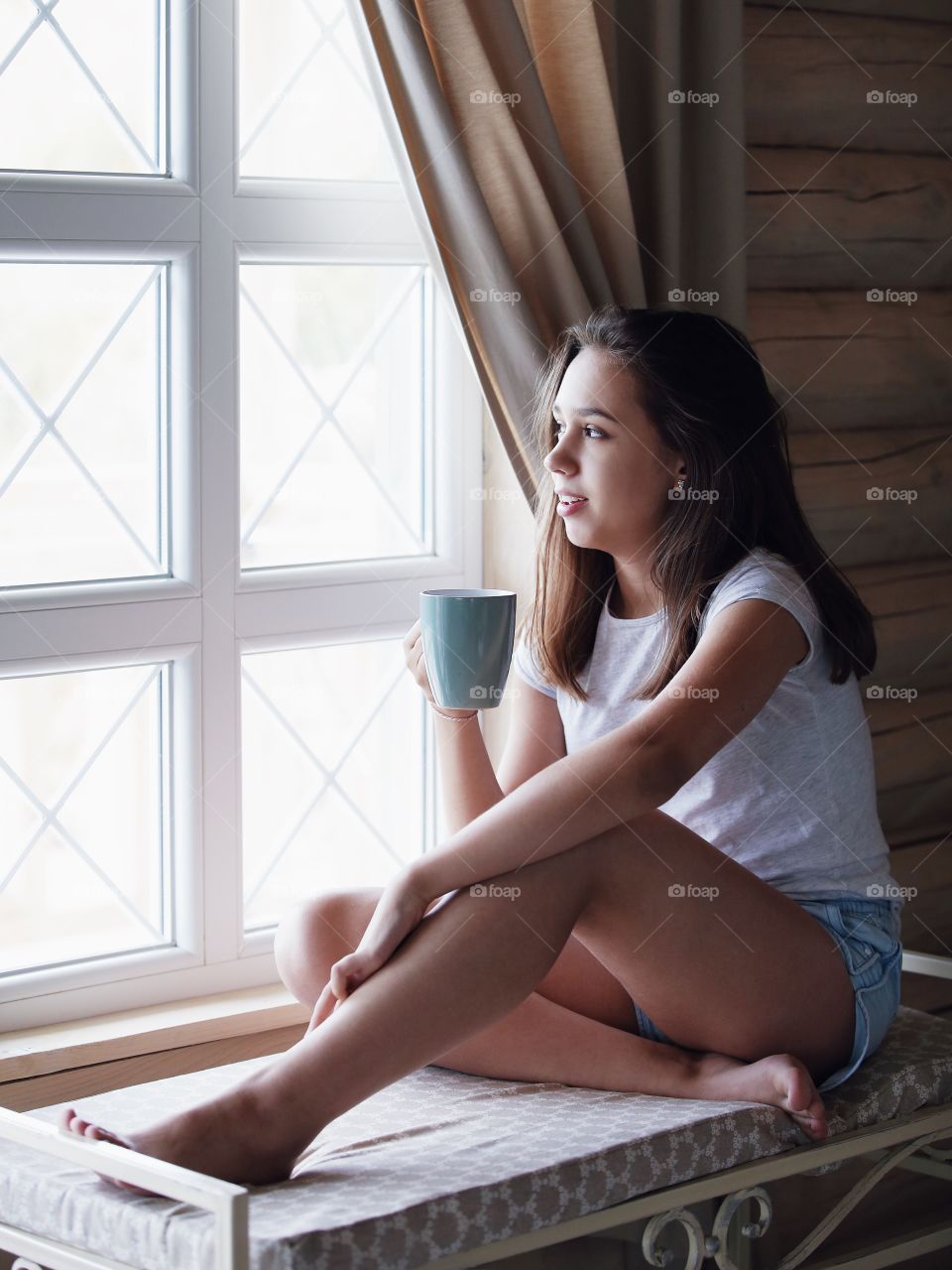 Young girl drinking tea near the window in the morning