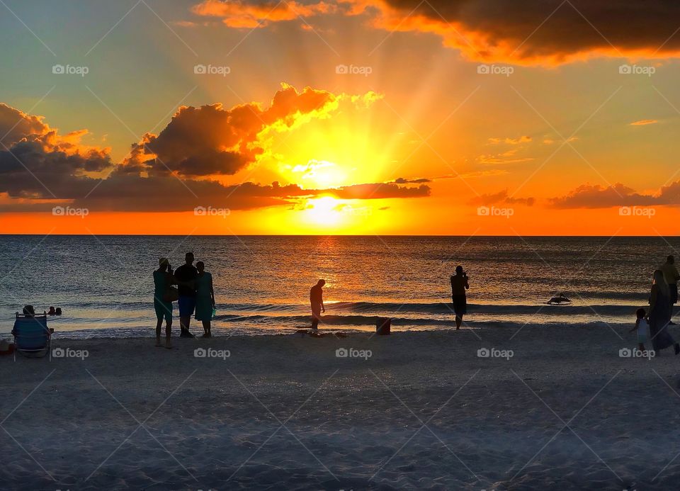Beachcombers gather to watch a spectacular ocean sunset.