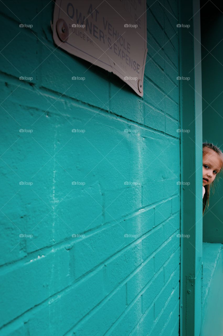 Little girl hiding behind the wall