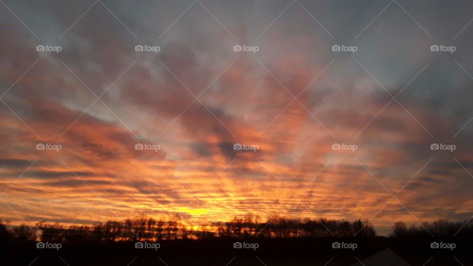 dramatic sunset fills the sky over a bare abandoned corn field