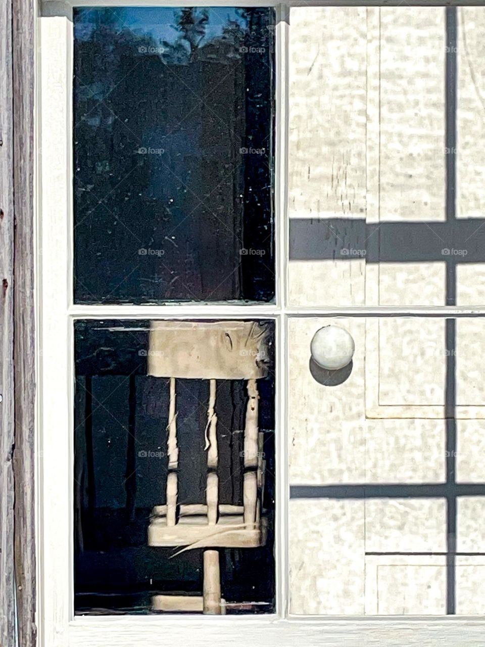 An old settle bench is partially revealed from the aged window of a country farmhouse.
