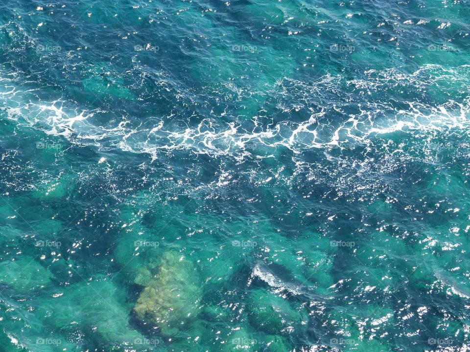 I love summer for its vibrant colors. The sun shines at its highest and the colors of the sea are brilliant. This image evokes the journey by the wake of a boat, the crystal clear waters reveal the seabed.