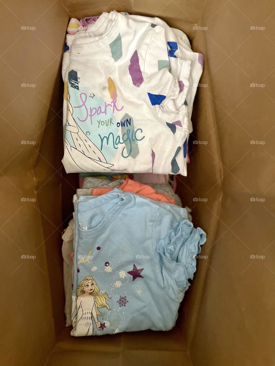 Donating toddler girl clothing, toddler clothing in a paper bag to donate, recycling clothing