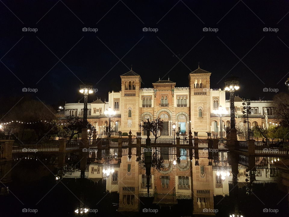 A pool in the dark in which an elegant building is reflected. Sevilla. Spain.