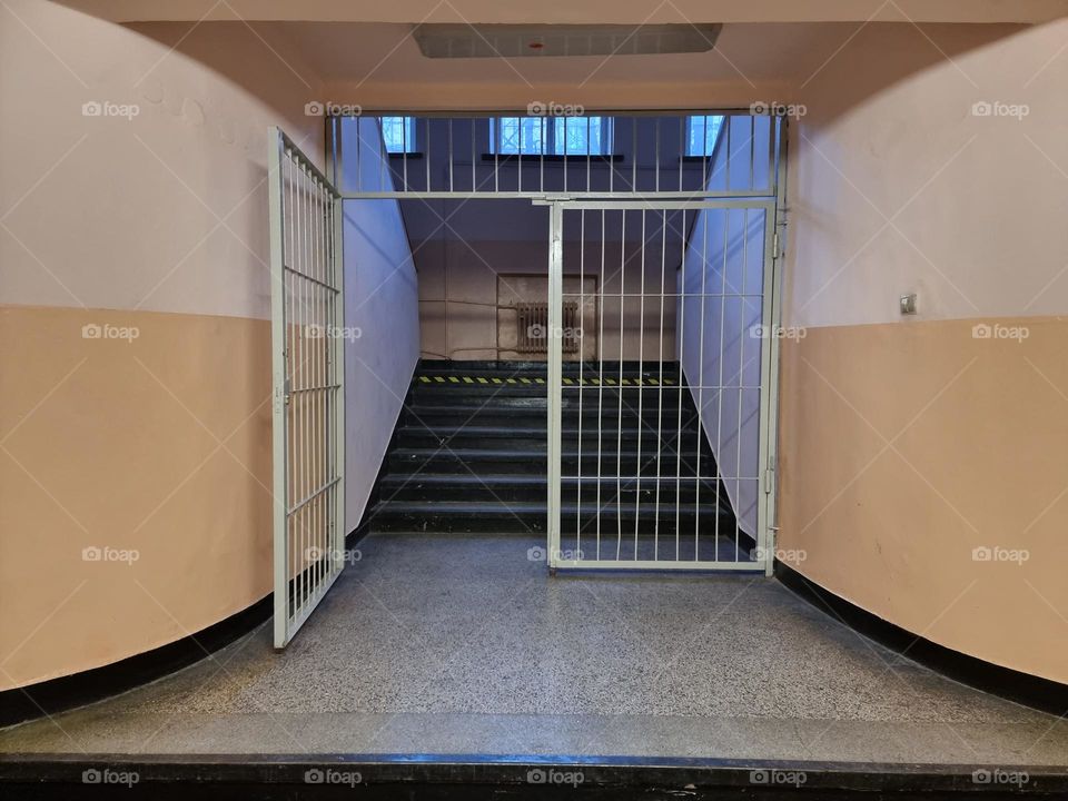 Corridor with steel doors of which one is opened, giving entry to dark stairs