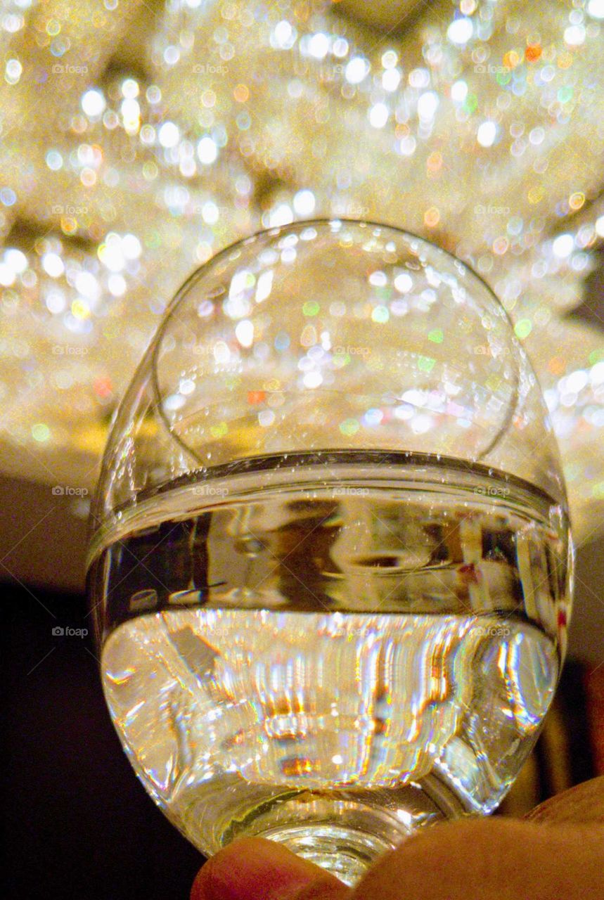 the chandelier's reflection on the wine glass at dinner party, beautiful colors.