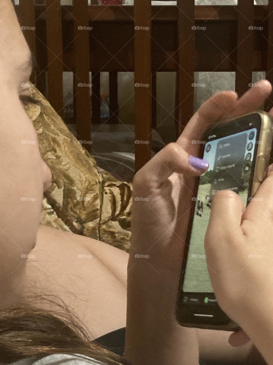 Menina à vontade no sofá mexendo no seu celular à noite.