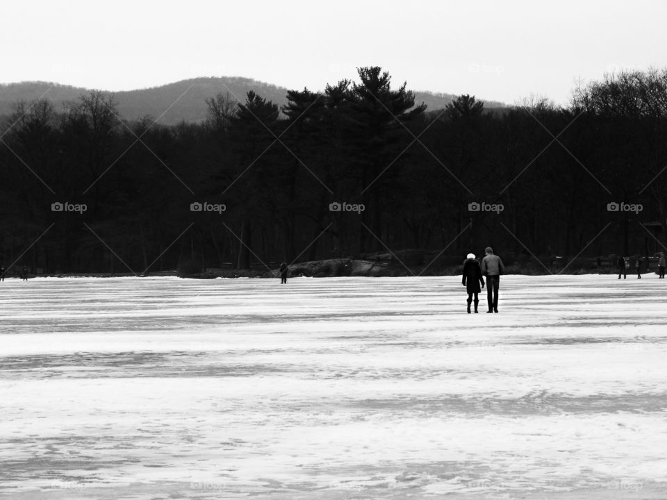 A couple walks across a frozen lake