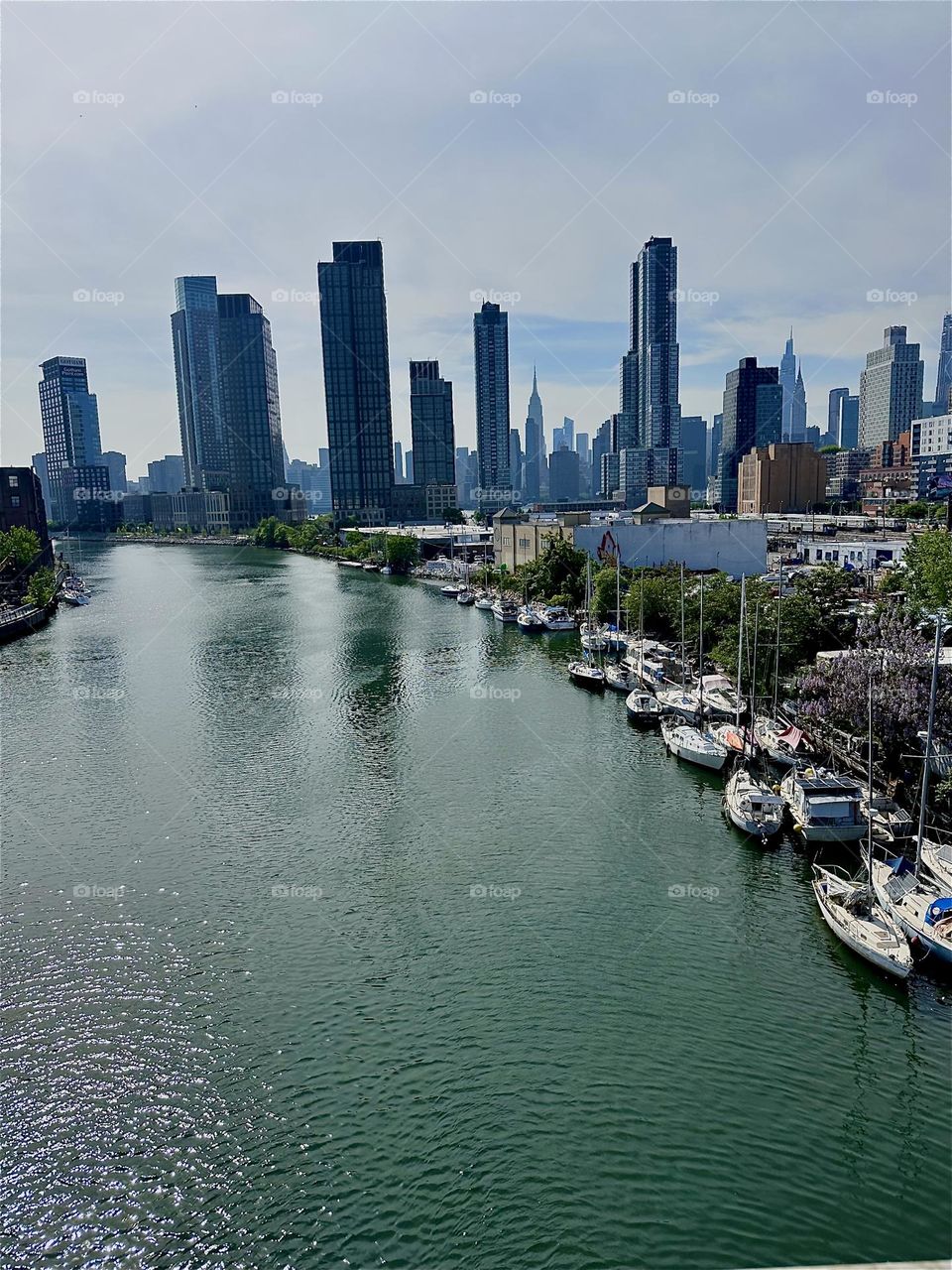 This is beautiful “Newtown Creek” seen from the “Pulaski Bridge” that connects LIC, Queens to “Greenpoint”, Brooklyn. Across the “East River” we see “Manhattan” including such landmarks as the “Empire State Building”. 2024. Hypnotic Productions