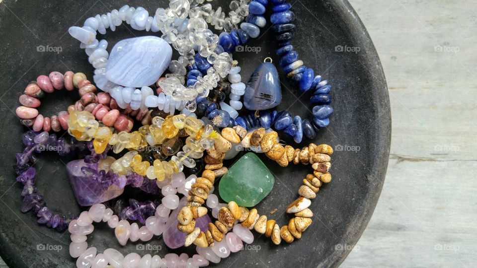 Black bowl with gem stones on a grey wooden background