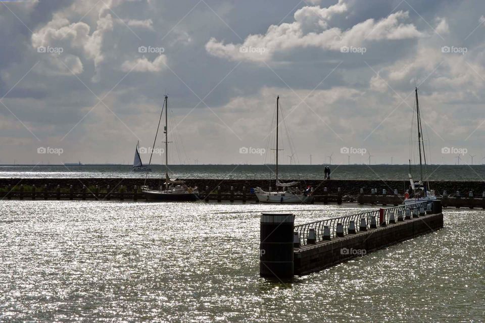 harbour of sea with sailing boats in the dawn with sparkling water lights reflection