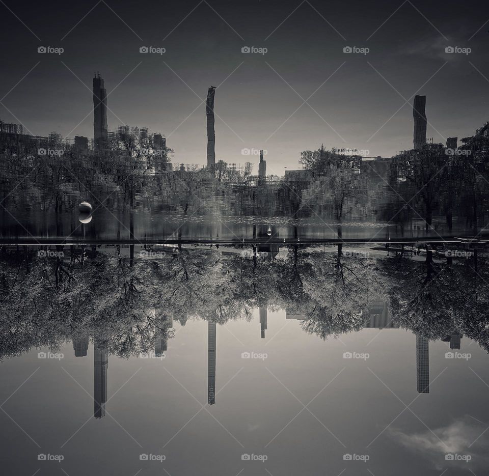 Reflections of buildings along Central Park South in a pond in the park