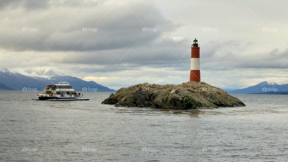 Tourist boat with a view of the Les Éclaireurs Lighthouse sailing the Beagle Channel in Ushuaia, Argentina.