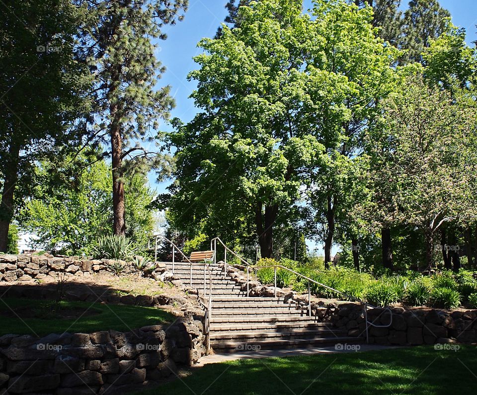 A brick stairway leading to a layered flower and rock garden in Pioneer Park in Bend in Central Oregon on a sunny spring day. 
