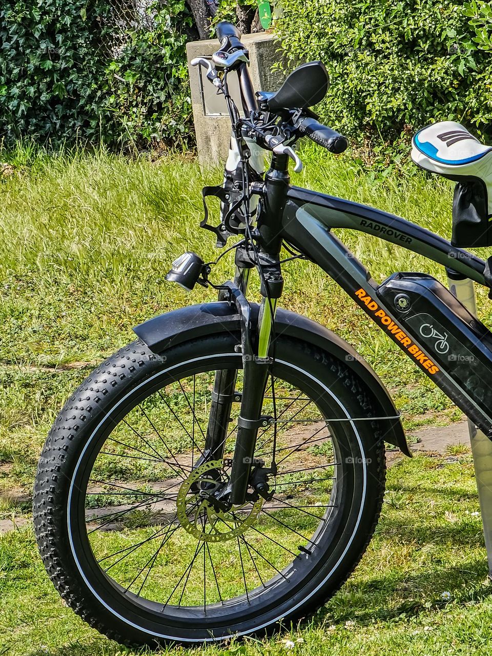 Black sports Bicycle parked in a park on a warm spring day with golf clubs ready for an adventure 