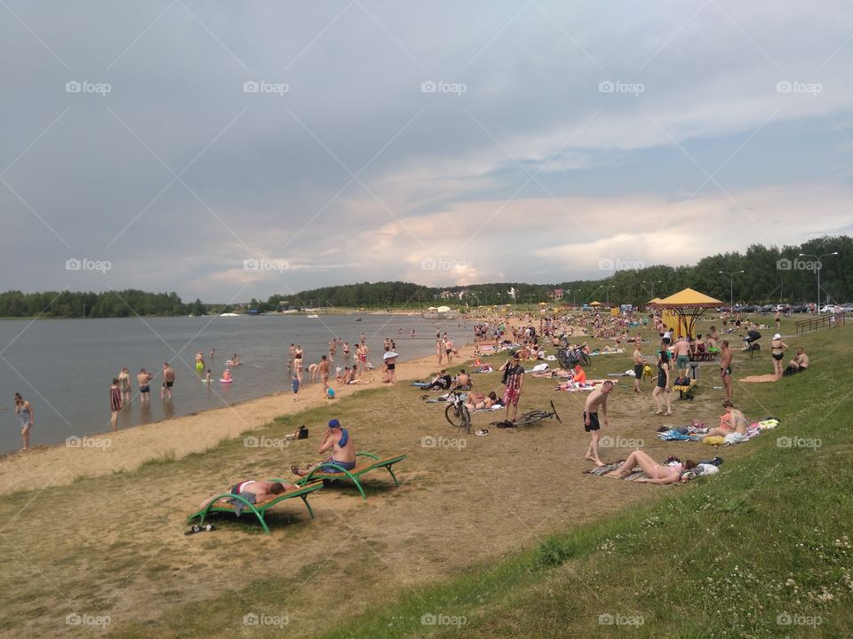 people resting on a lake shore summer time