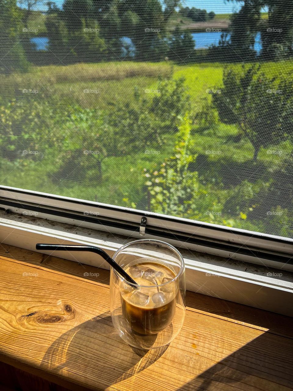 Inspiring cold cappuccino with ice in a beautiful glass with straw under the hot summer sun