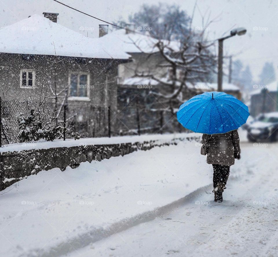 Blue umbrella in the winter storm