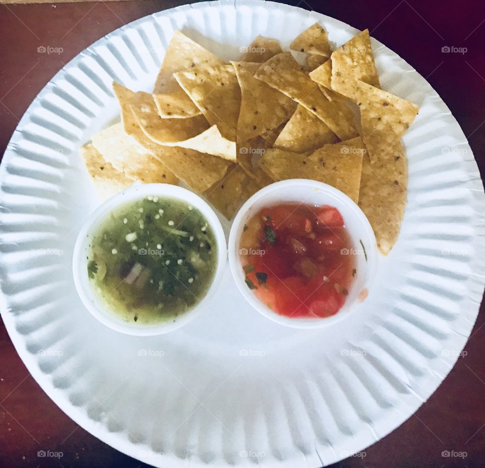 Chips and salsa on a white plate, green salsa and red salsa, a great Mexican appetizer. 