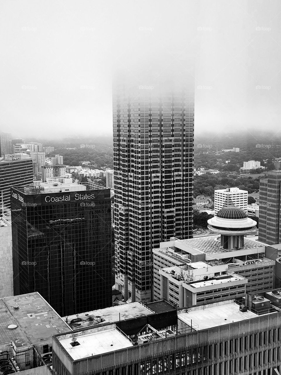A skyscraper disappears into low hanging cloud cover on a late summer day