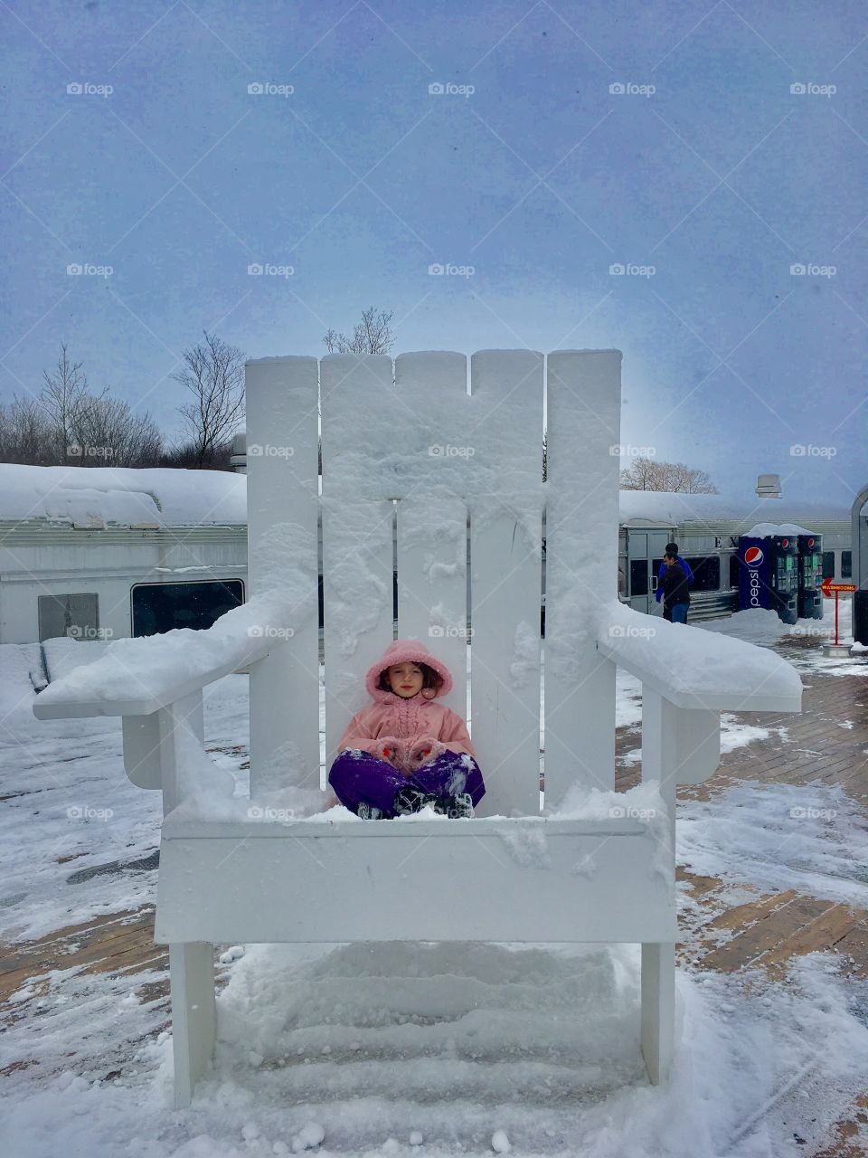 Little girl sitting on big snowy chair