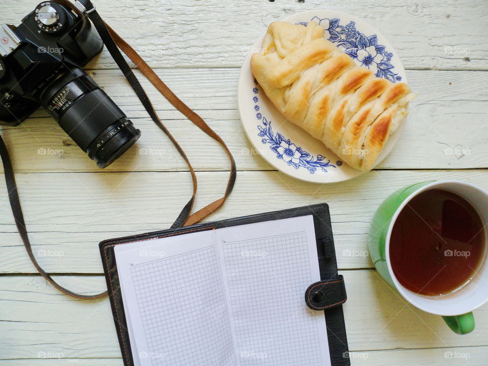 apple pie, a cup of tea, a notebook and an old film camera